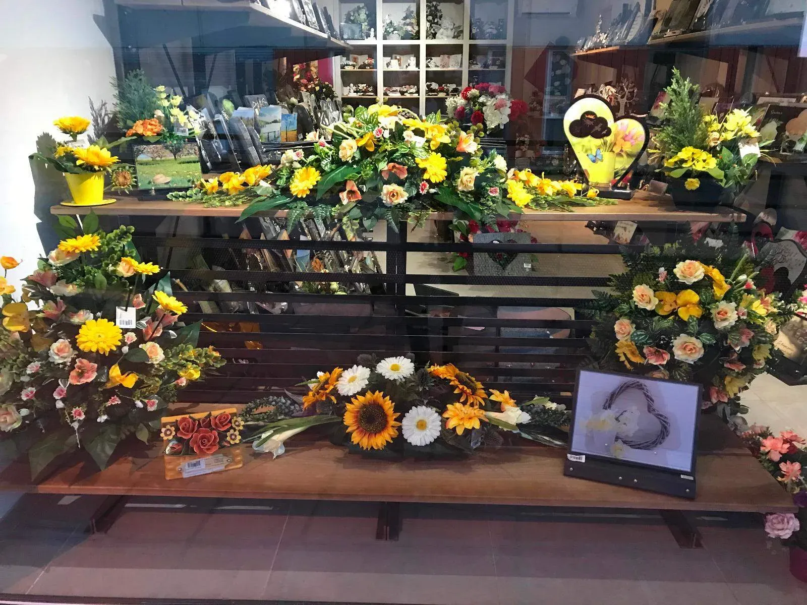 Présentation en vitrine de bouquets, tournesols et arrangements pour obsèques.